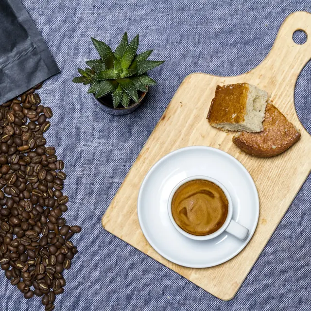 Café coado numa tábua de madeira, com grãos torrados ao lado.