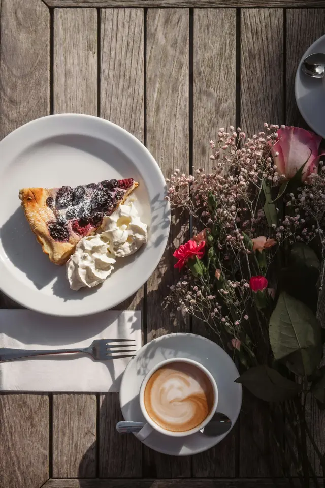 Fatia de torta de frutas vermelhas com chantilly e café.